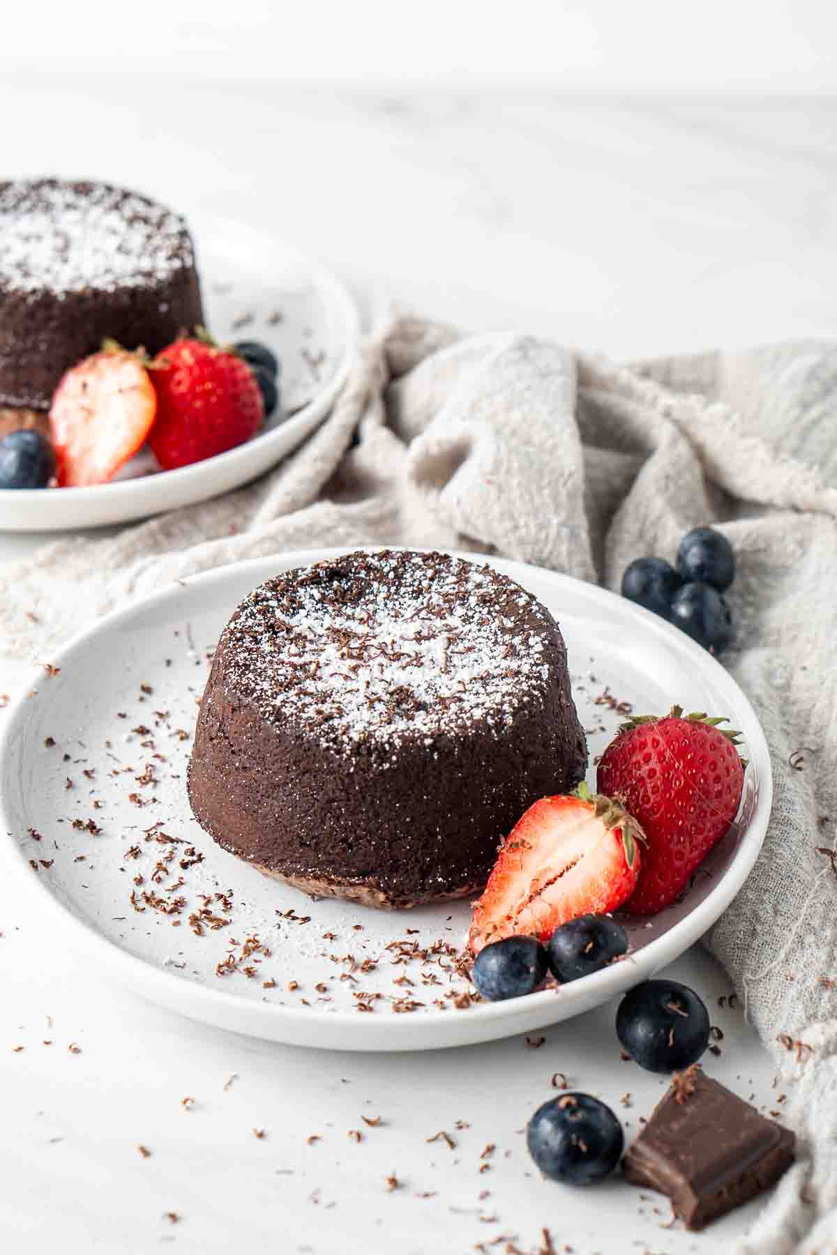 Chocolate lava cake on a white plate, dusted with icing sugar and fresh berries.