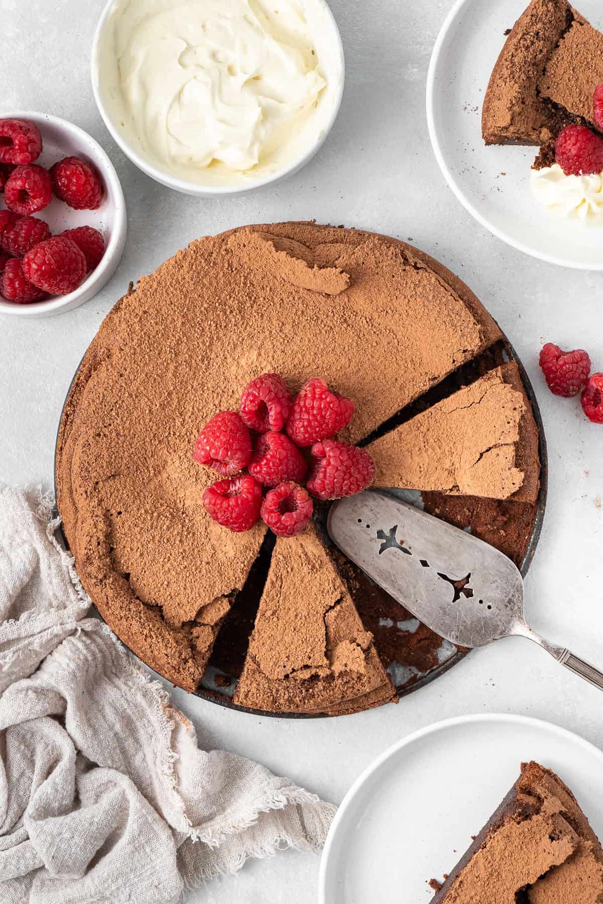 Flourless chocolate cake cut into slices with fresh raspberries. 