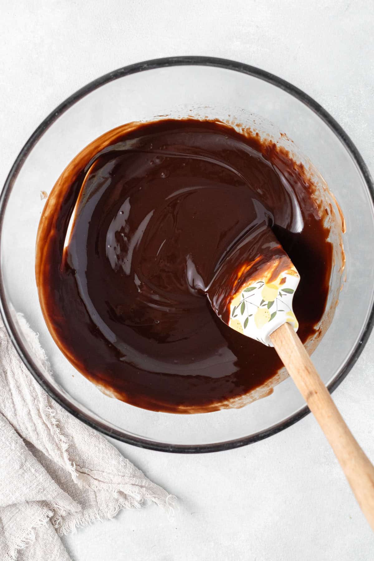 The melted chocolate and butter in a glass bowl with a spatula. 