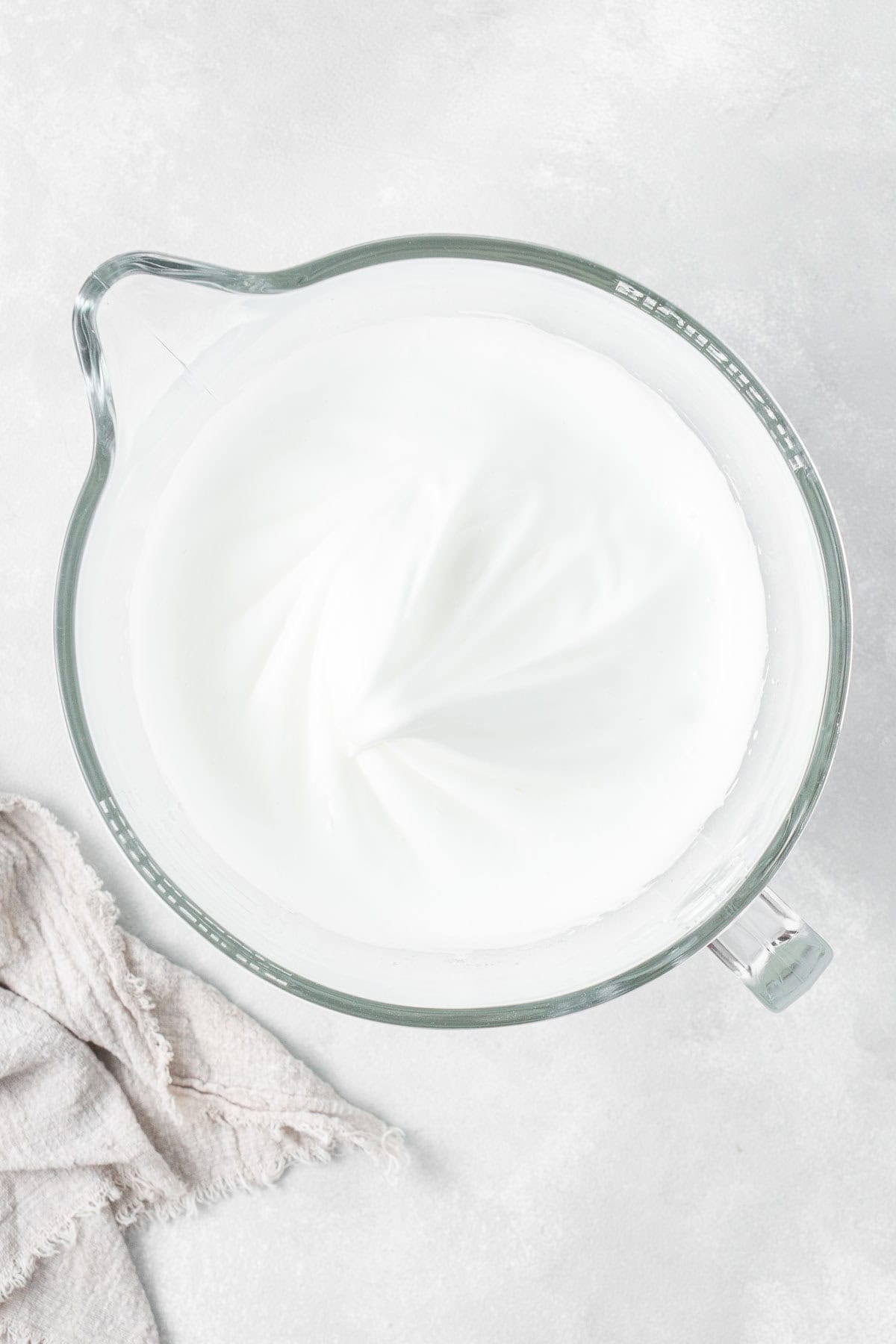 The whipped egg whites and sugar in a stand mixer bowl.