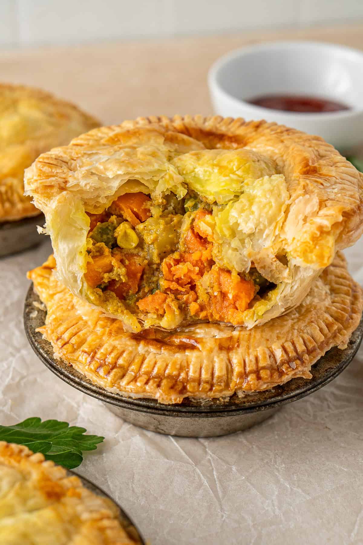 Two vegetables pies stacked on top of each other one with a bite taken.