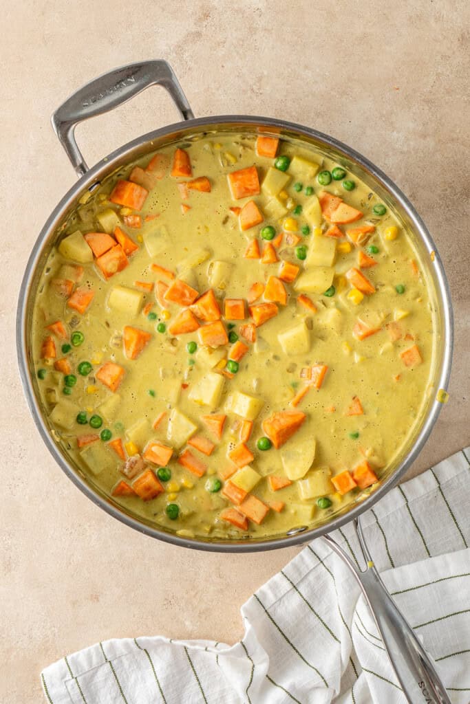 The coconut and curry powder in the frying pan with the vegetables.