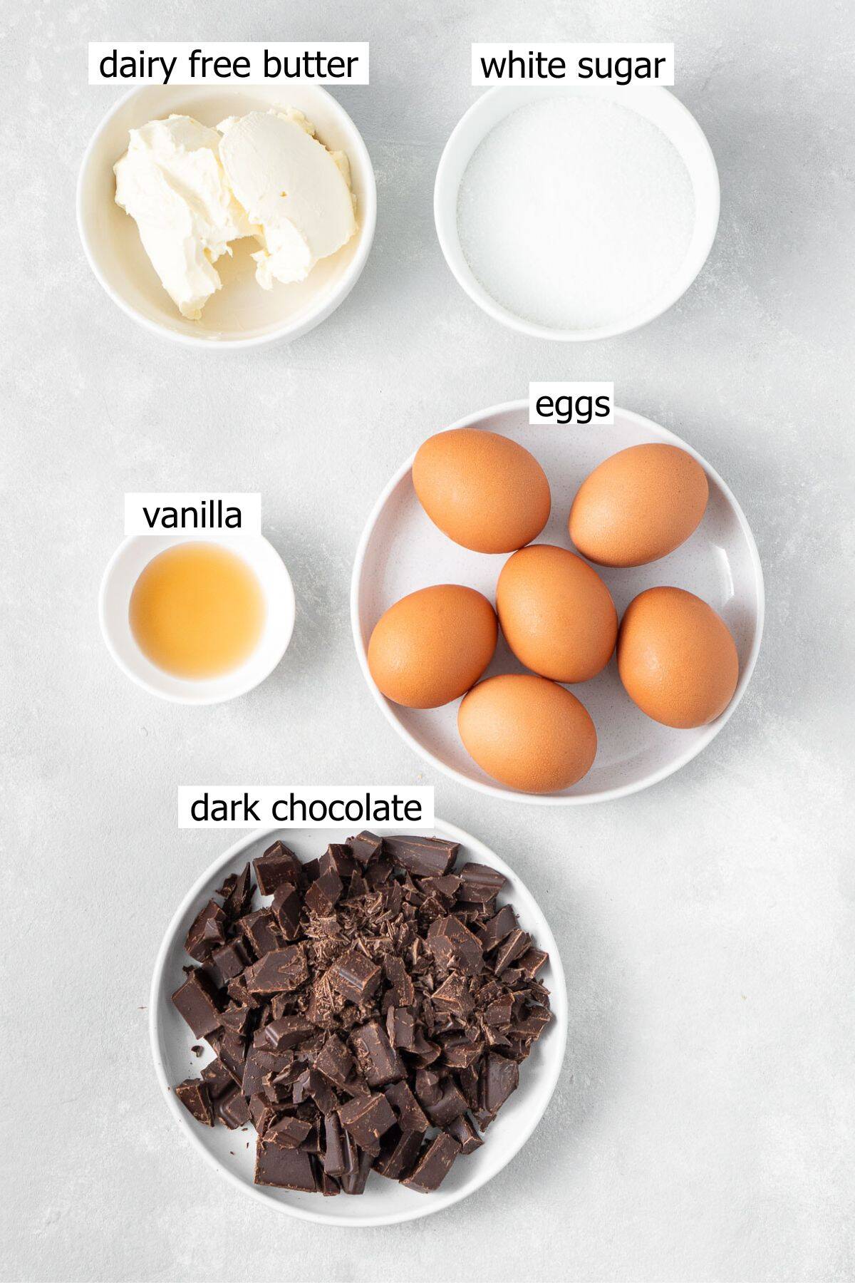 All ingredients needed to make flourless chocolate torte laid out in white bowls.