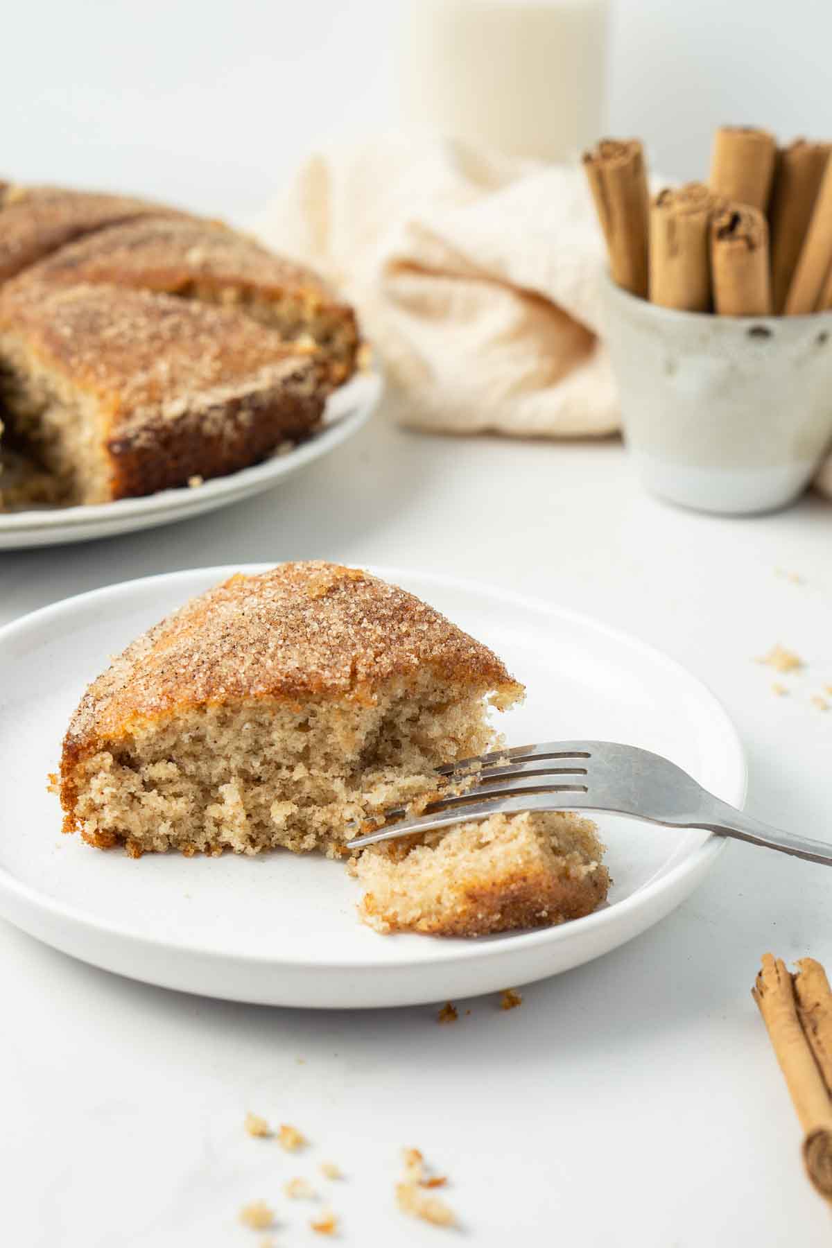 Slice of cinnamon tea cake on a plate with a fork.