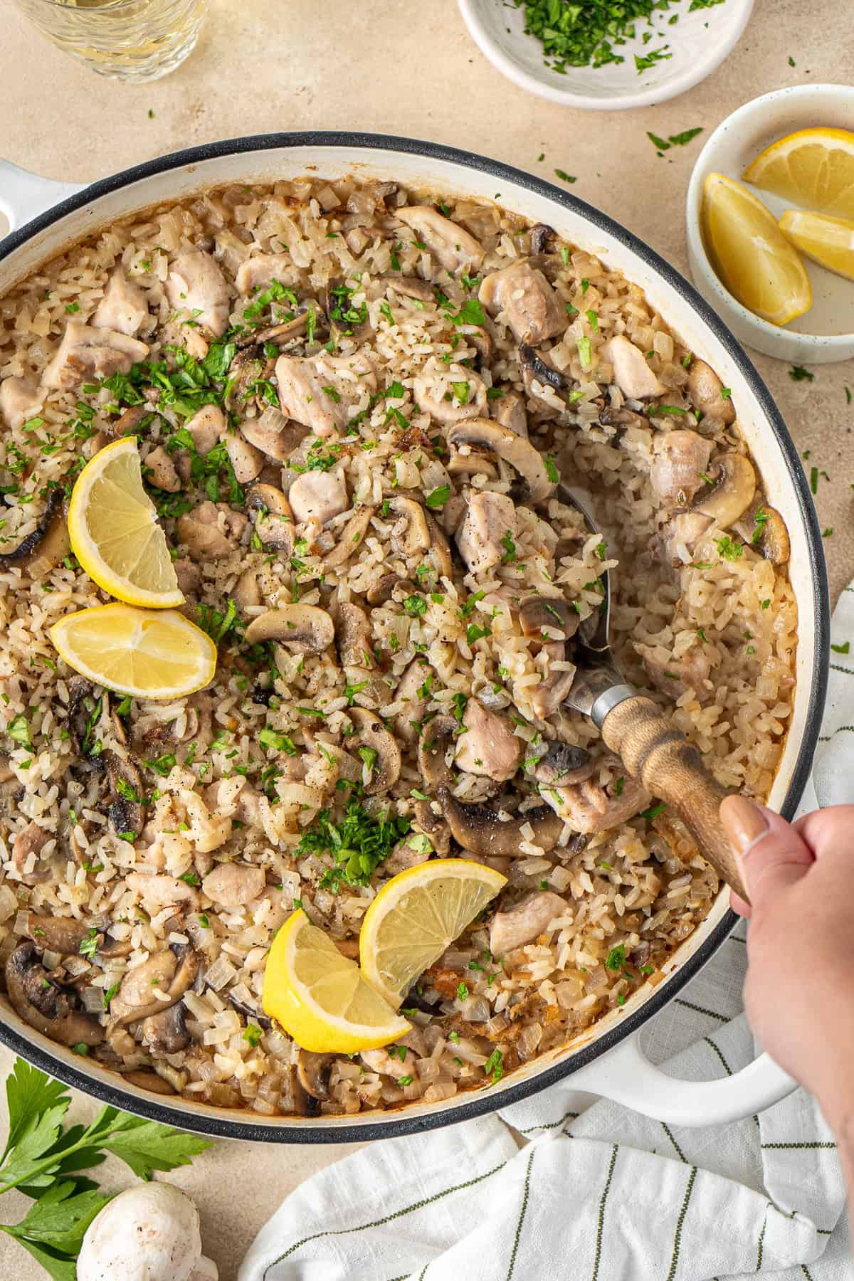 A hand serving a baked chicken and mushroom risotto.