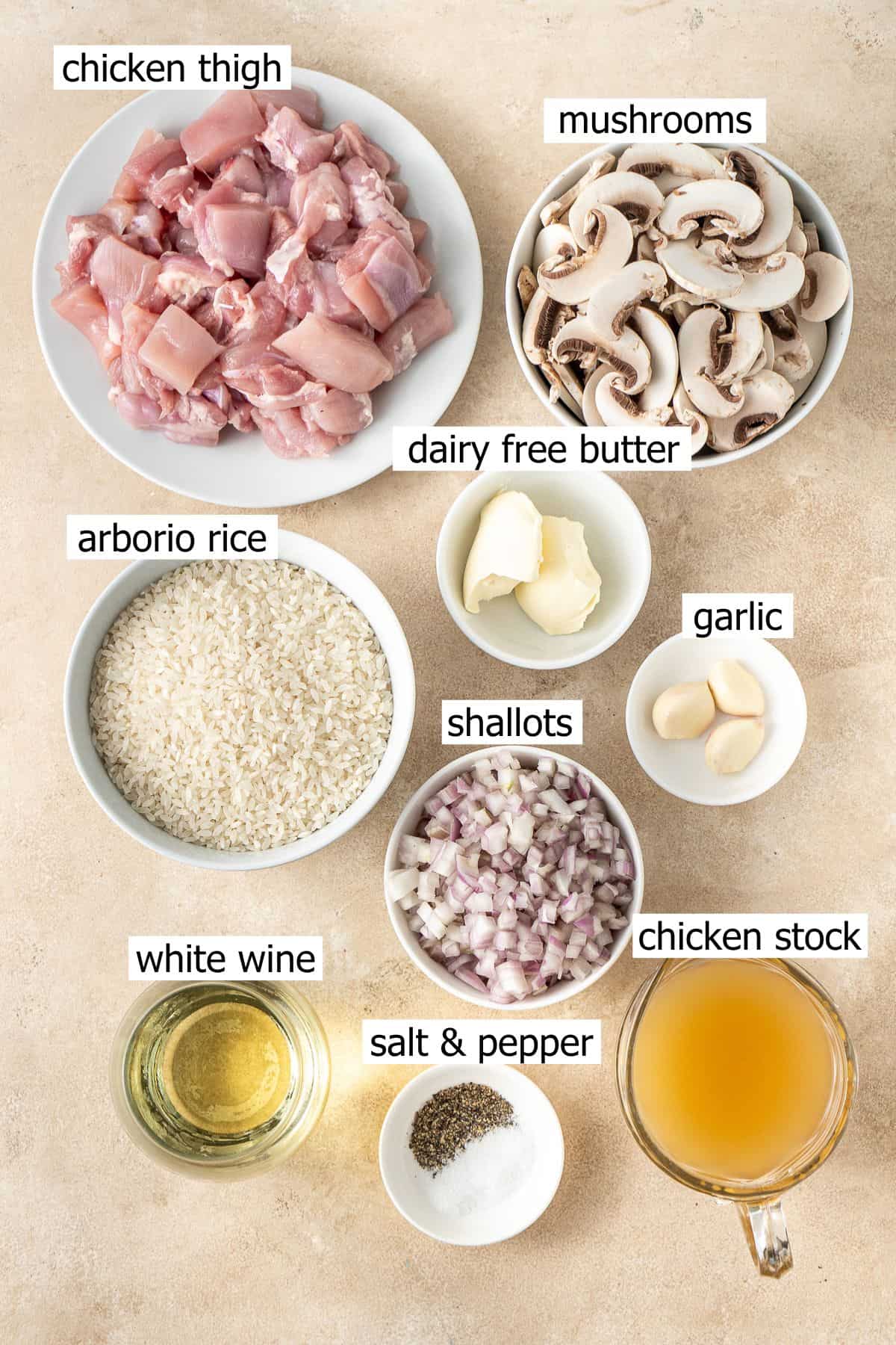 All ingredients needed to make oven-baked chicken and mushroom risotto laid out in small bowls.