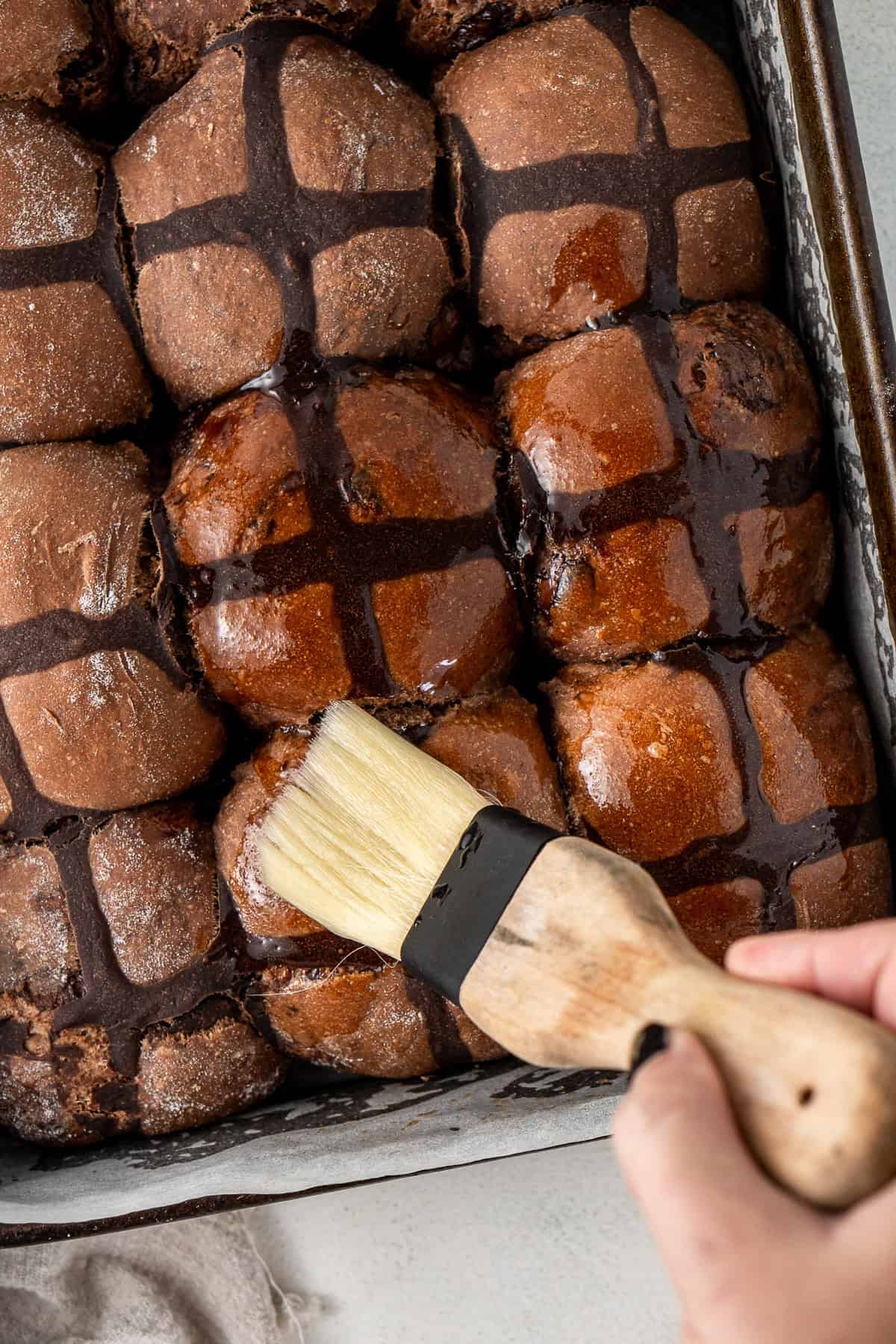 Brushing the buns with the sugar syrup glaze.