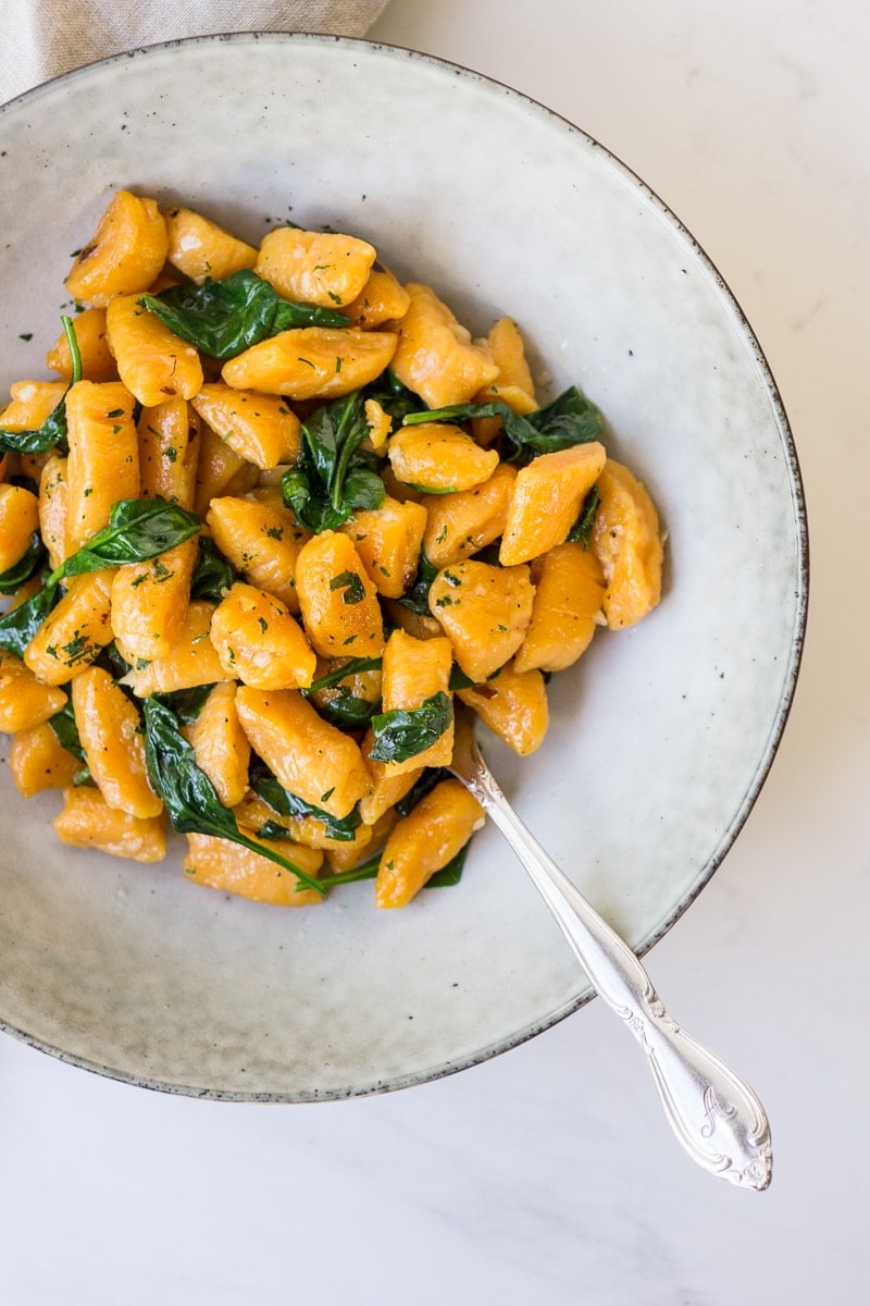 Homemade Sweet Potato Gnocchi with Garlic and Spinach in bowl with fork
