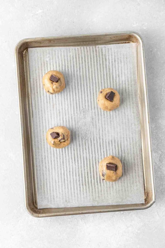 Chocolate chip cookie dough balls in a baking tray.