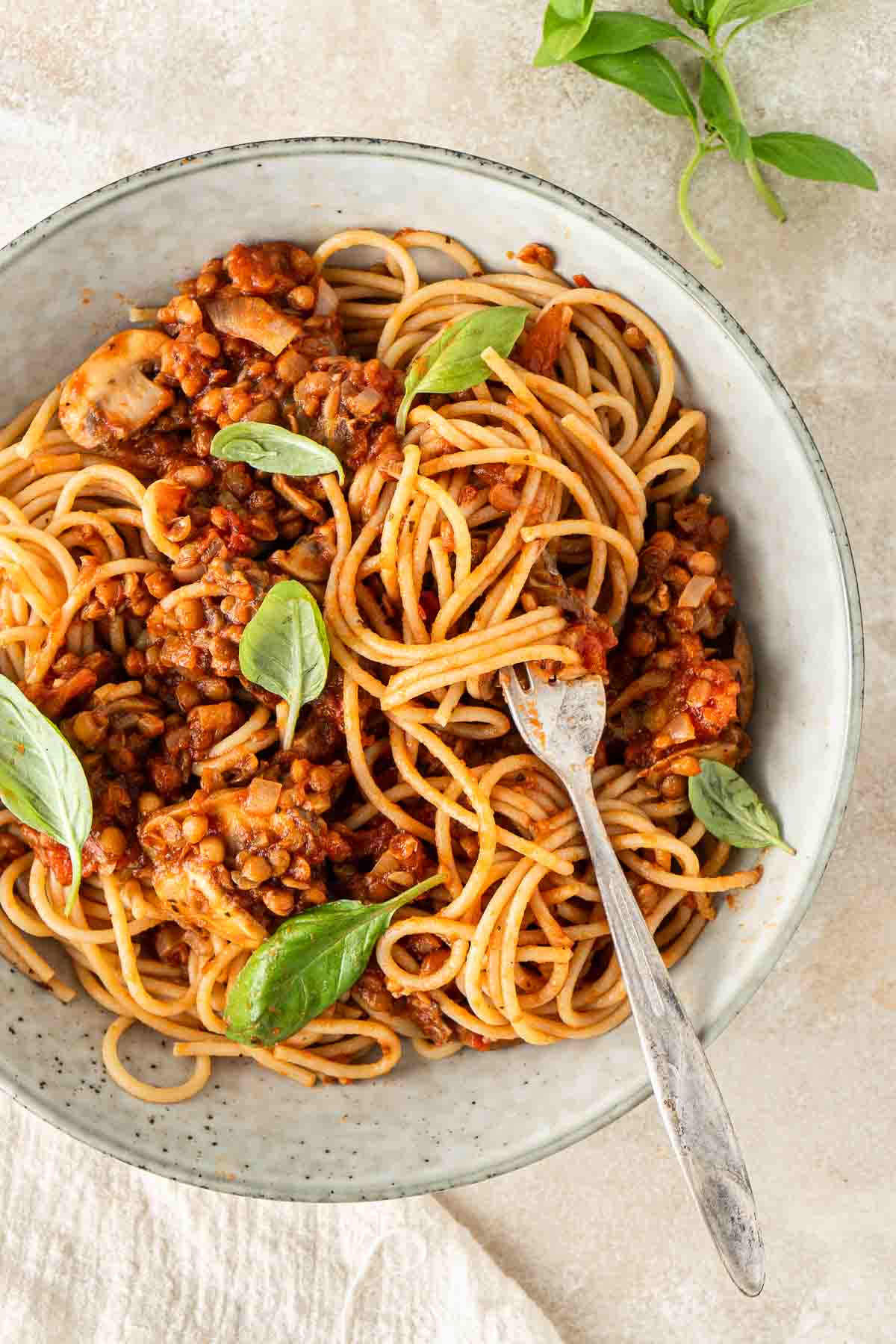 Bolognese mixed with the spaghetti in a bowl with a fork.