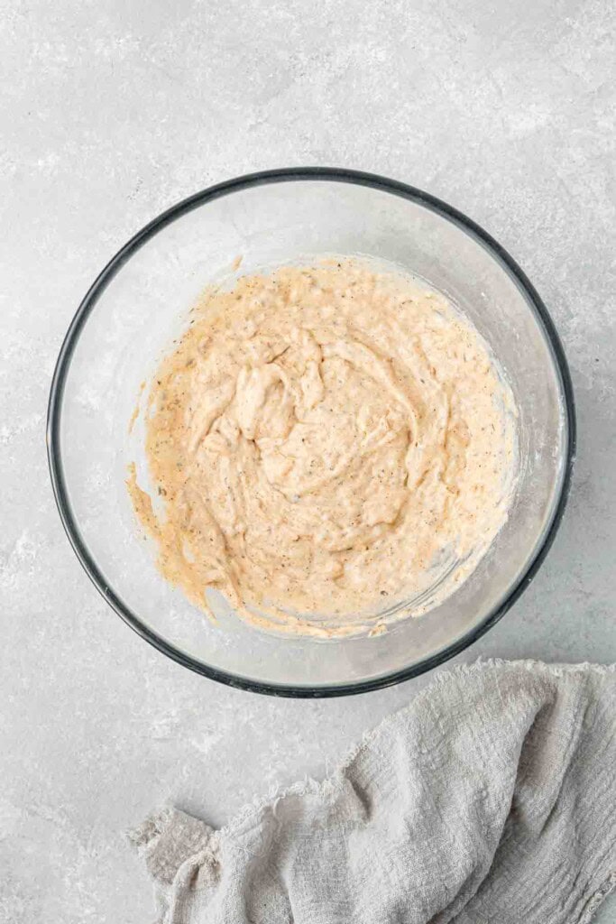 Mixing up the fritter batter in a glass mixing bowl.