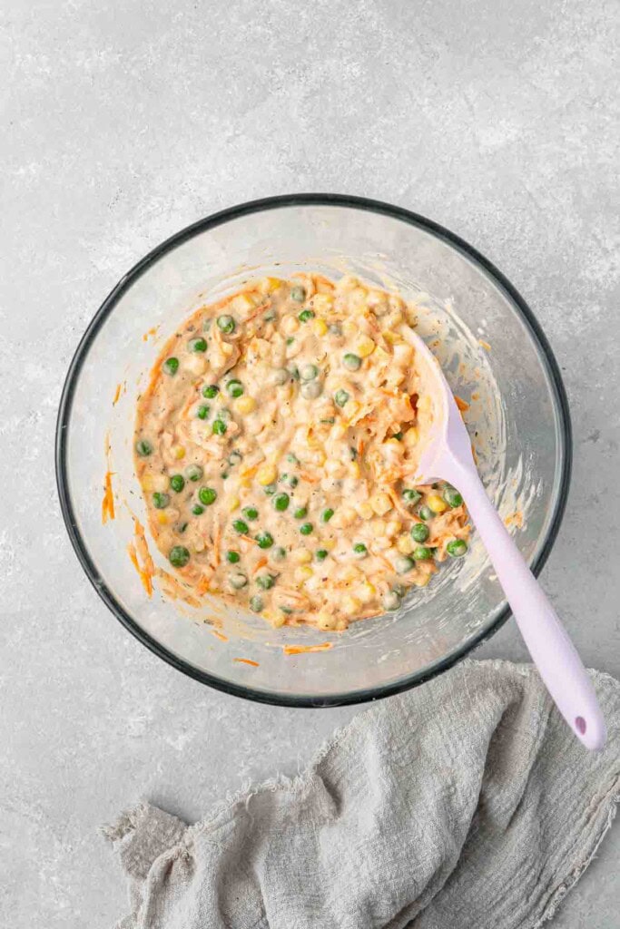 Vegetable fritter batter in a glass mixing bowl with a spatula. 