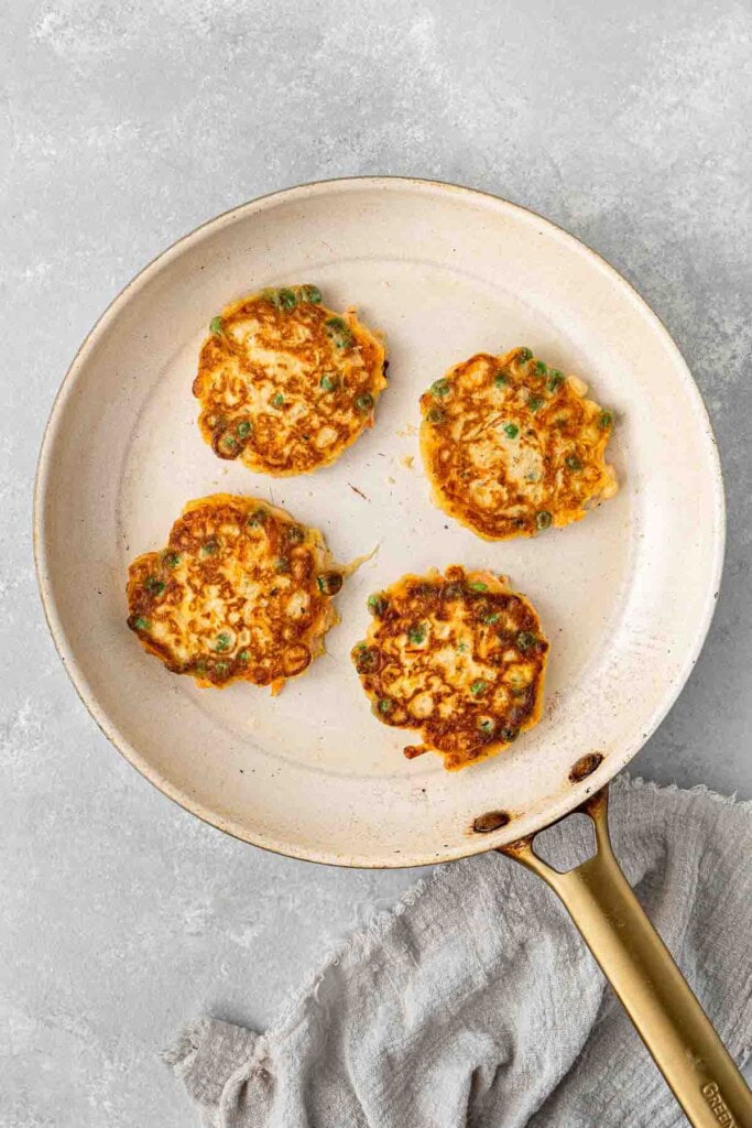 Vegetable fritters cooked in a large frying pan.