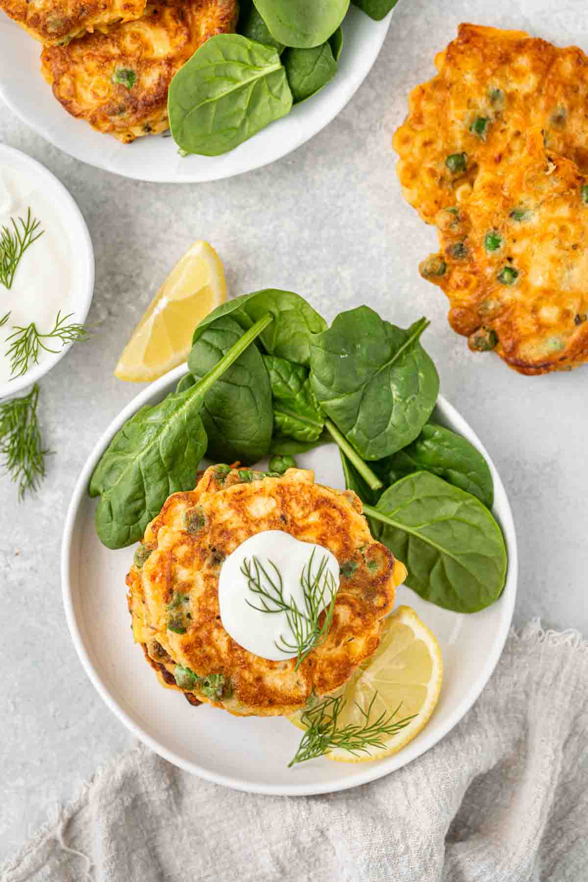 A white plat with spinach leaves and vegetable fritters.