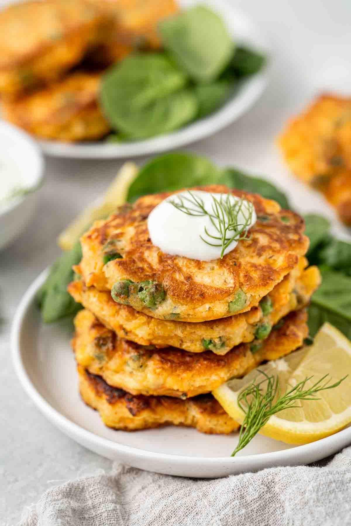 A stack of vegetable fritters topped with greek yoghurt. 