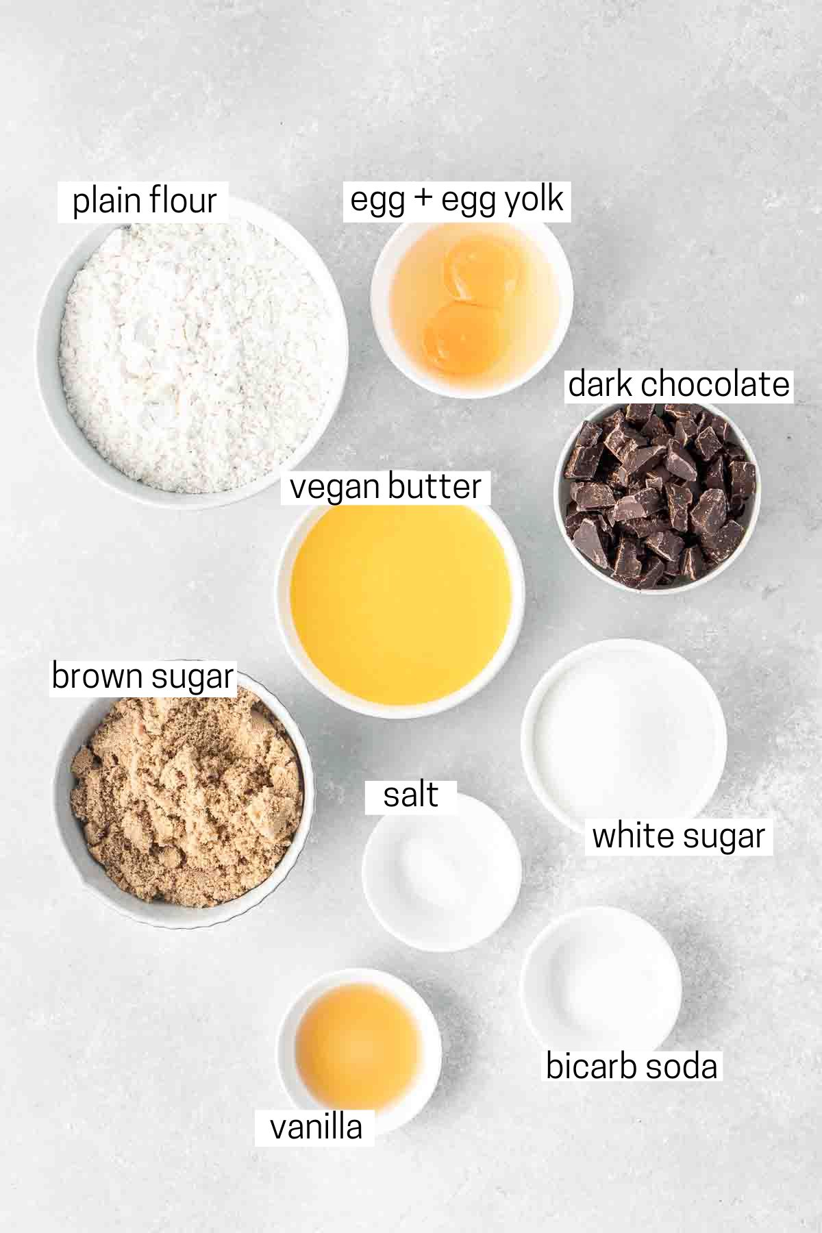 All ingredients needed for chocolate chip cookies laid out in small bowls.