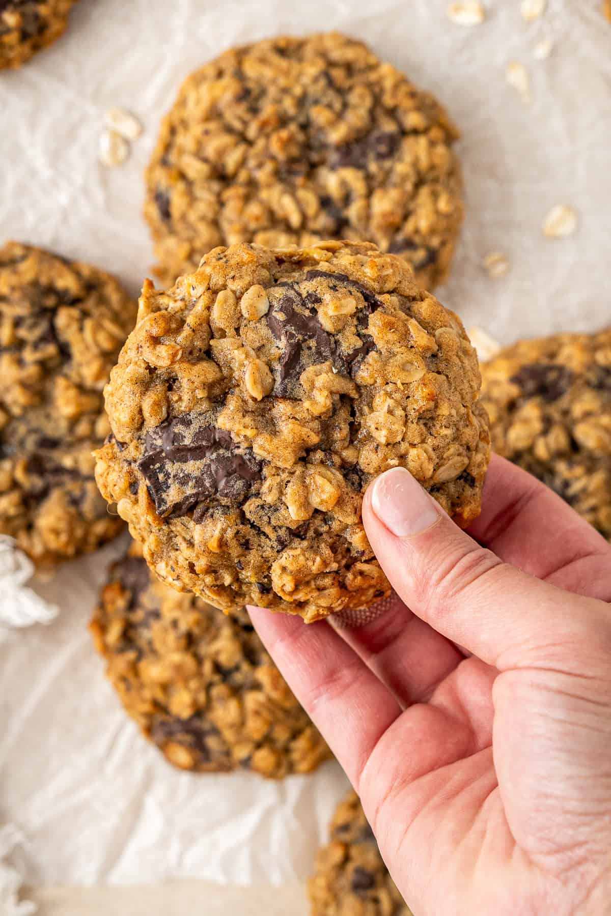A hand holding up a banana oat chocolate cookie.