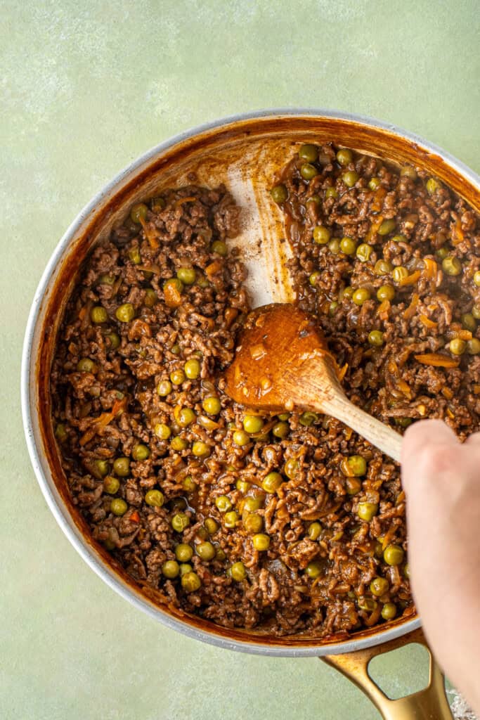 A wooden spoon showing the consistency of the mince mixture.