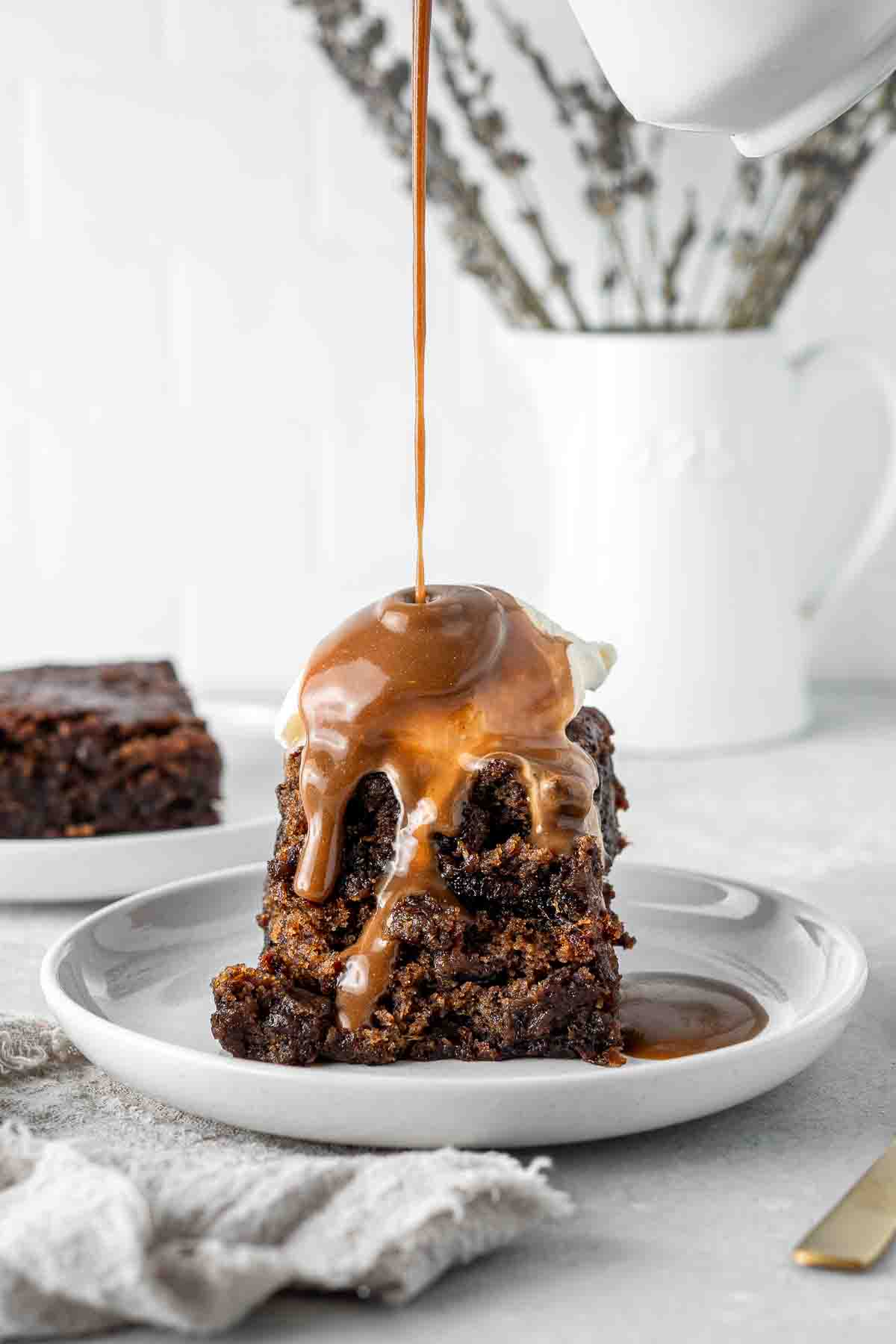 Drizzling caramel sauce over vegan sticky date pudding.
