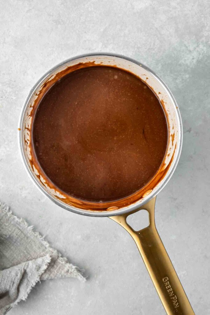 The thickened caramel sauce in a small saucepan.
