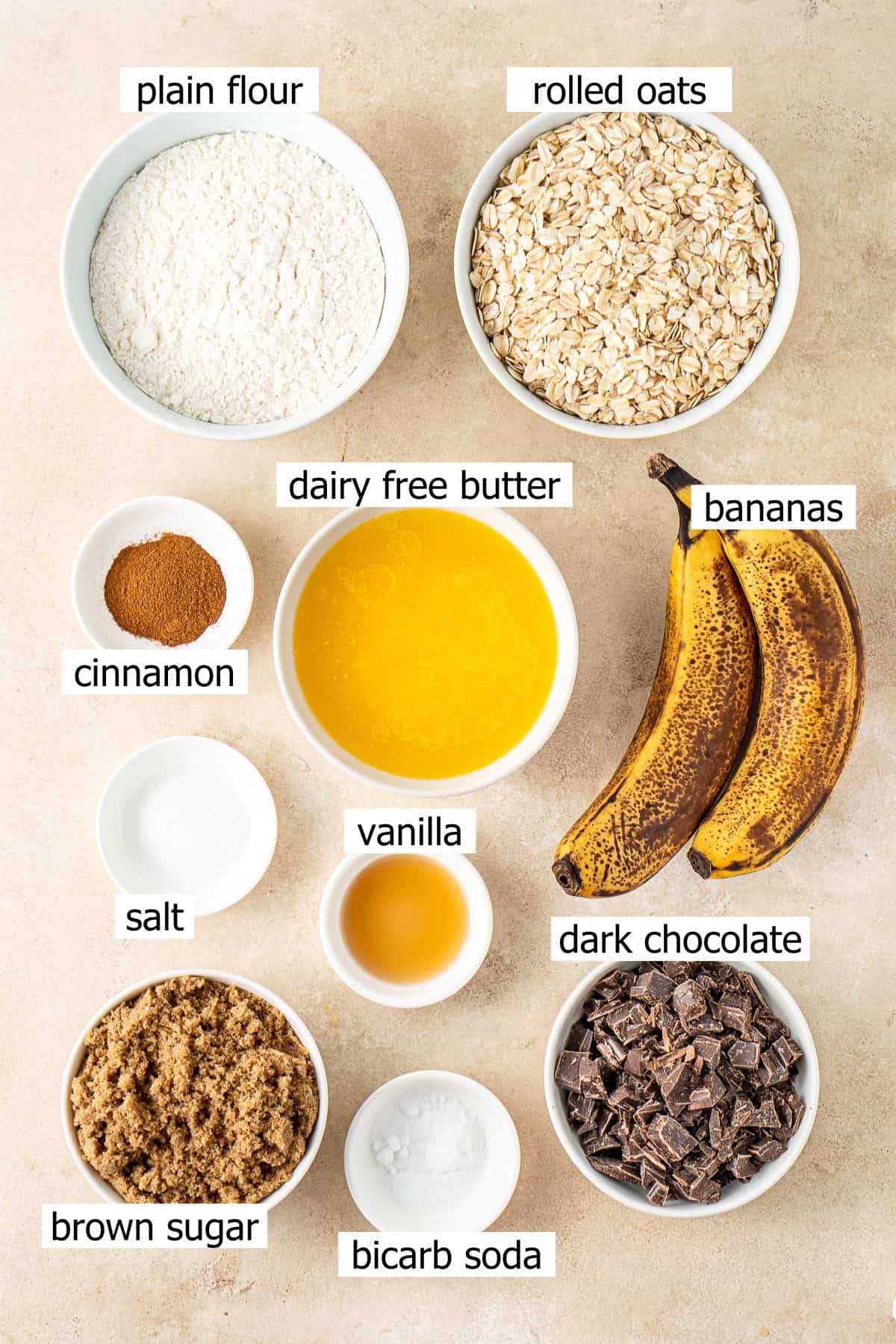 All ingredients needed to make banana oat chocolate chip cookies laid out in small bowls.