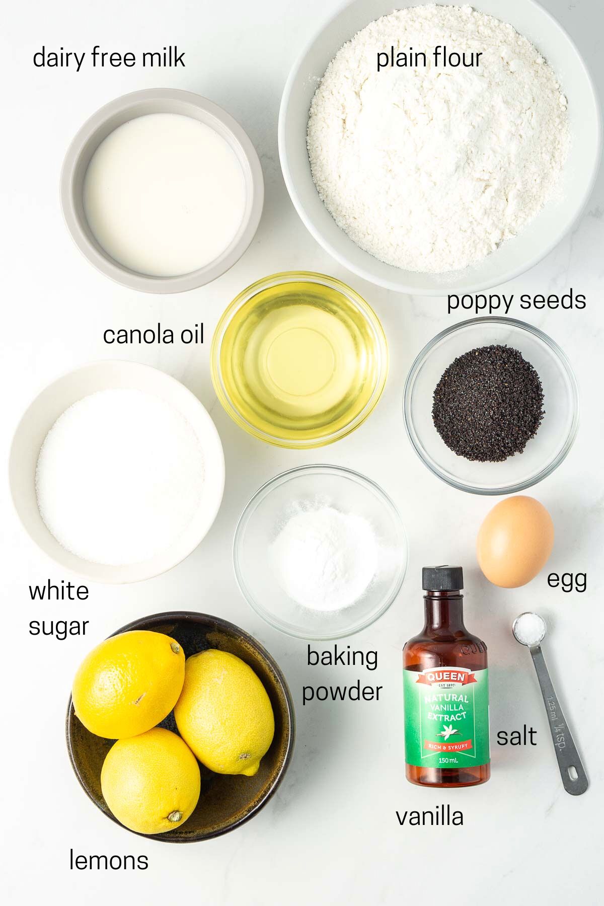 All ingredients needed for lemon poppy seed muffins laid out in small bowls.