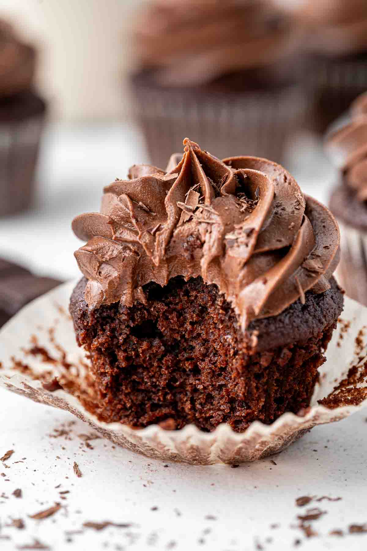 Close up of a vegan chocolate cupcake with a bite taken.