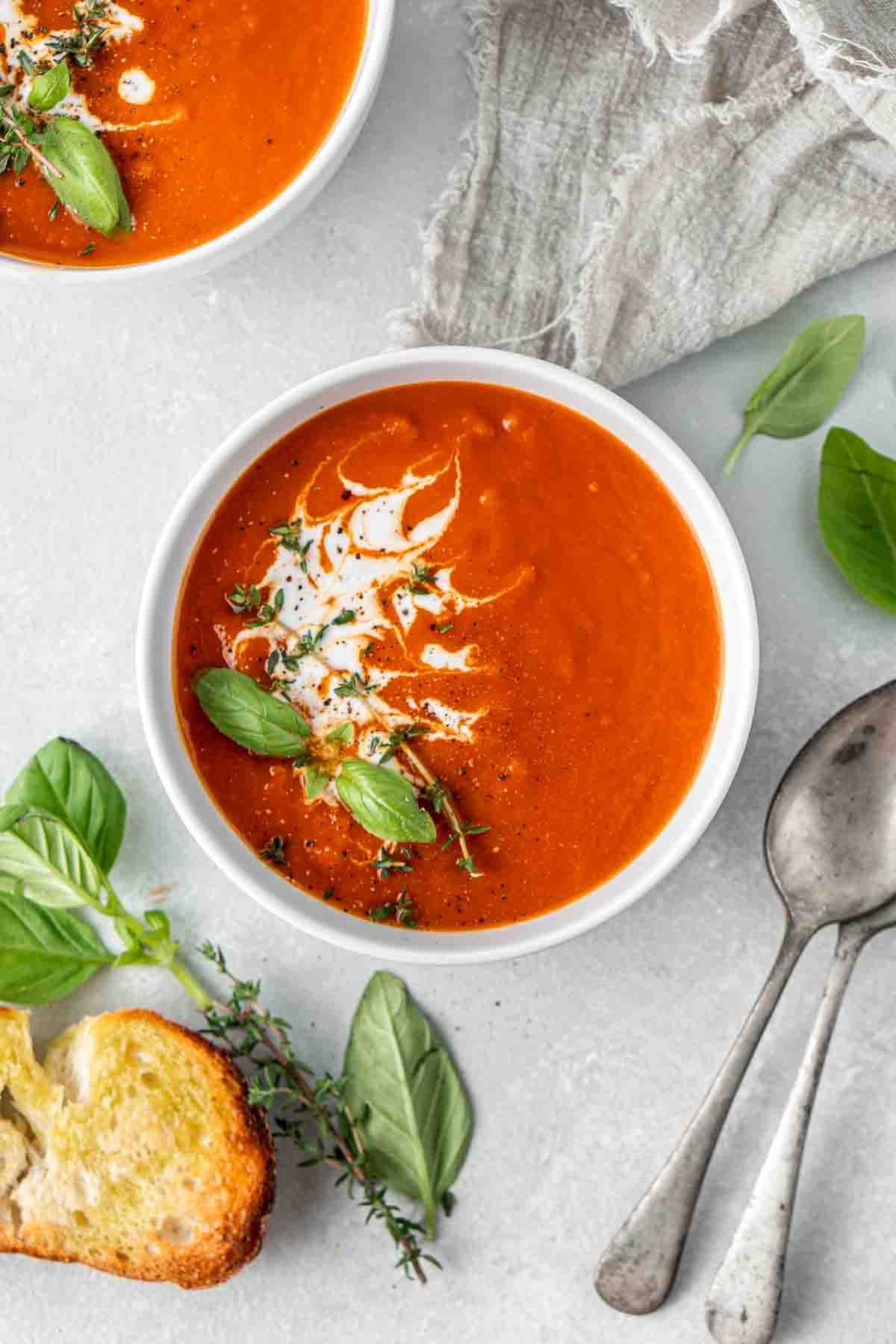 A bowl of vegan tomato soup with toasted bread and herbs. 