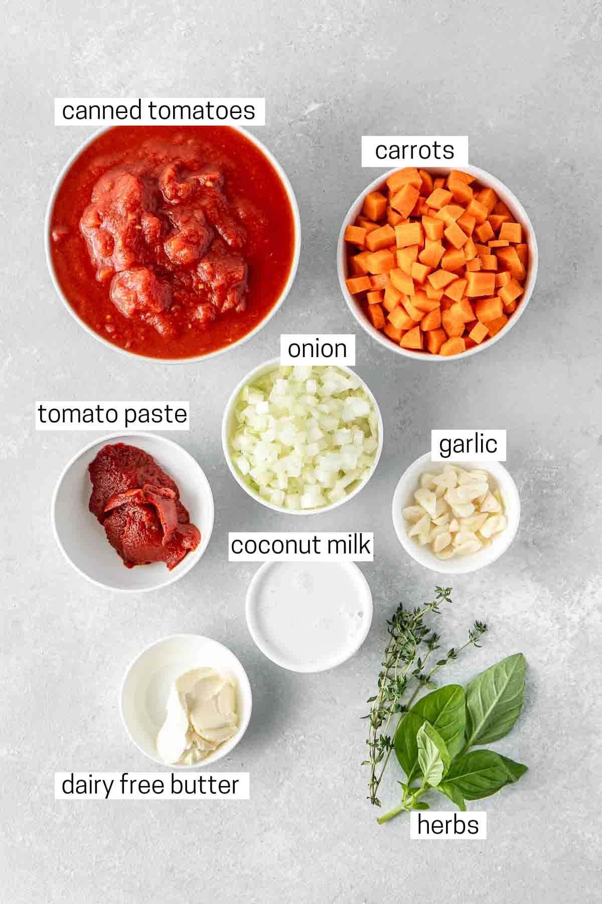 All ingredients needed to make vegan tomato soup laid out in small bowls.