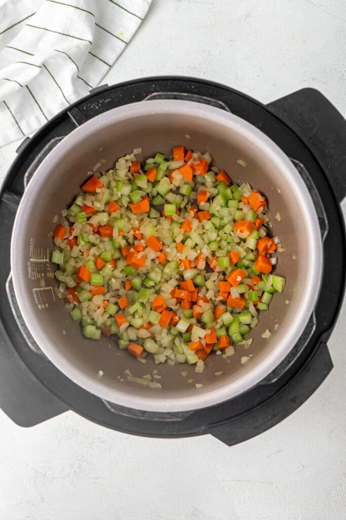 Sautéing the onions, carrot and celery in the pressure cooker.