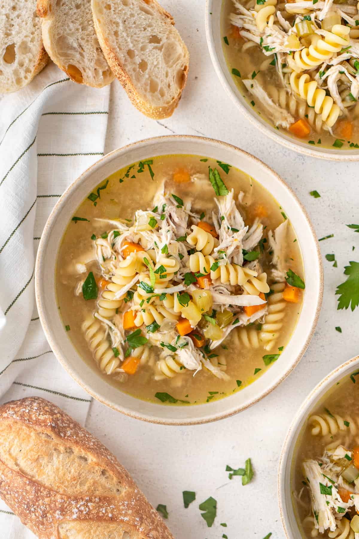 Pressure cooker chicken noodle soup served into bowls with fresh bread and garnished with parsley. 