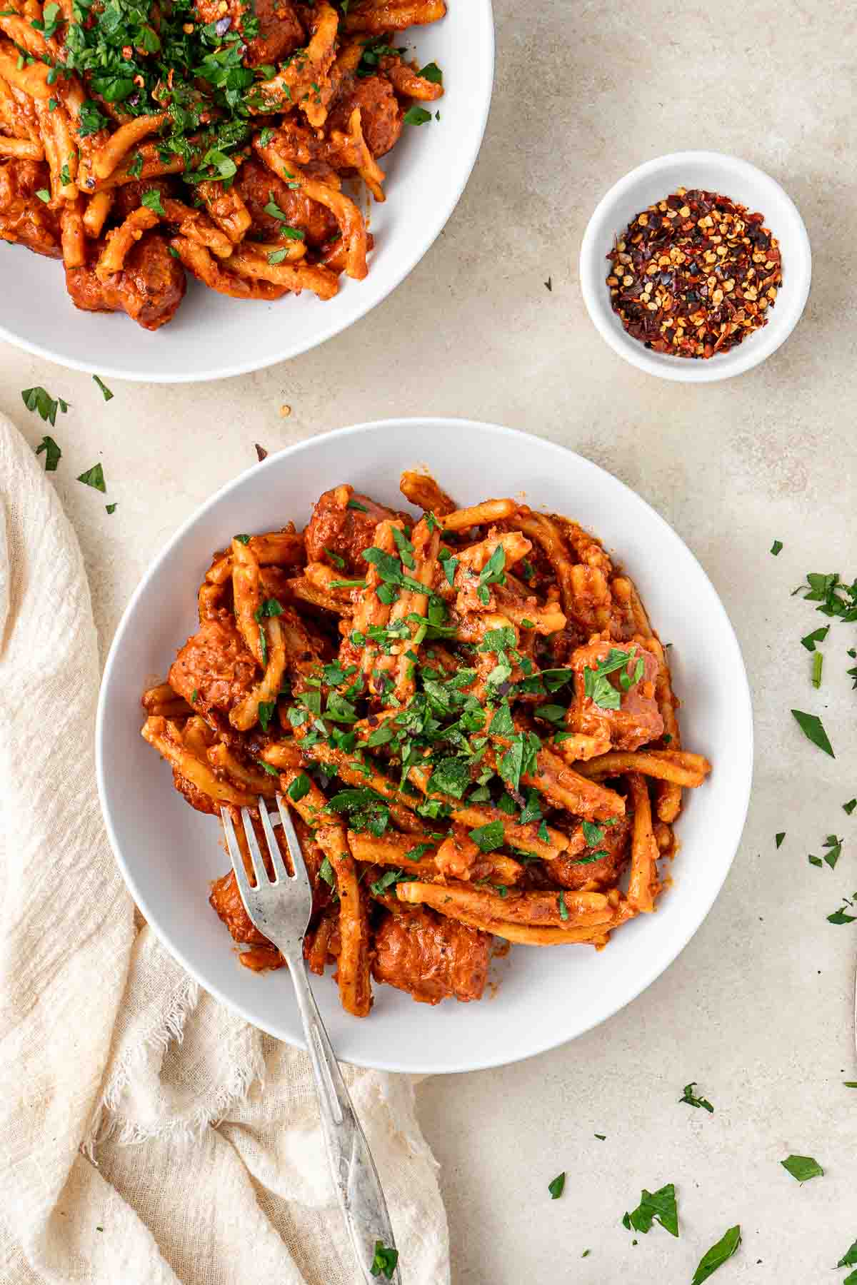 A bowl of spicy sausage pasta with parsley and chilli. 