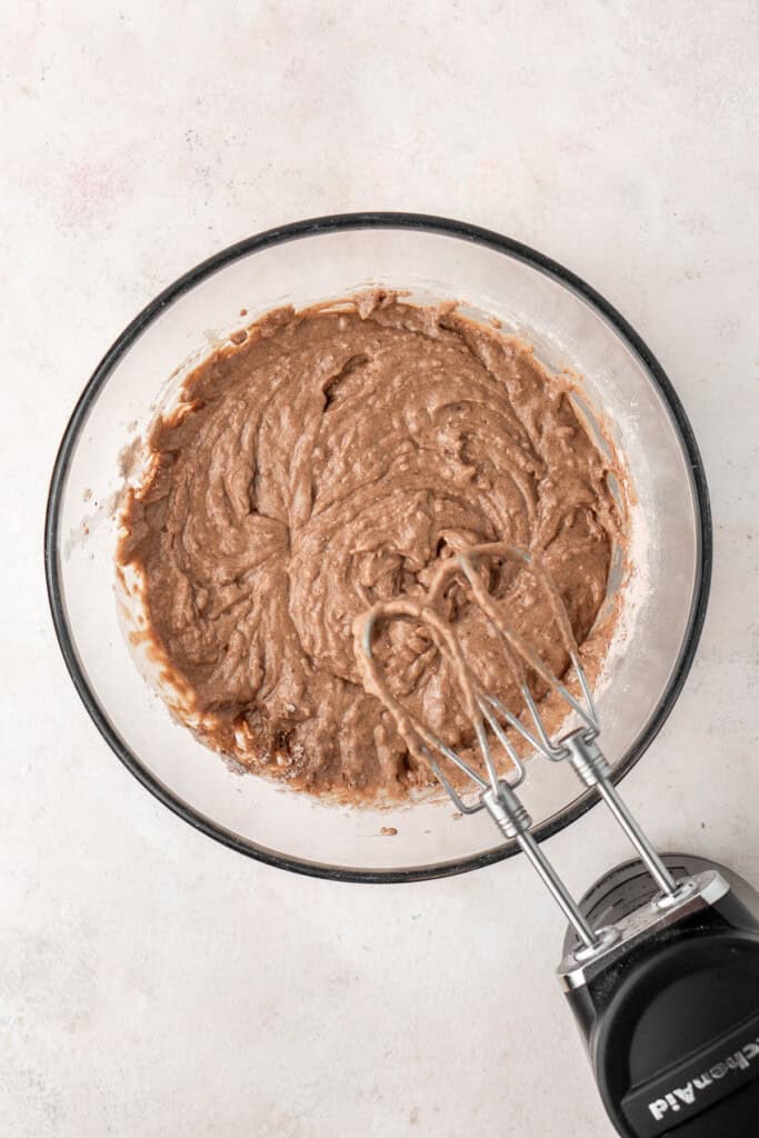 Mixing together the cupcake batter in a glass bowl.