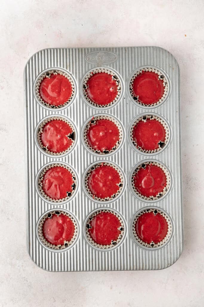 The red cupcake batter in a muffin tin ready to bake.