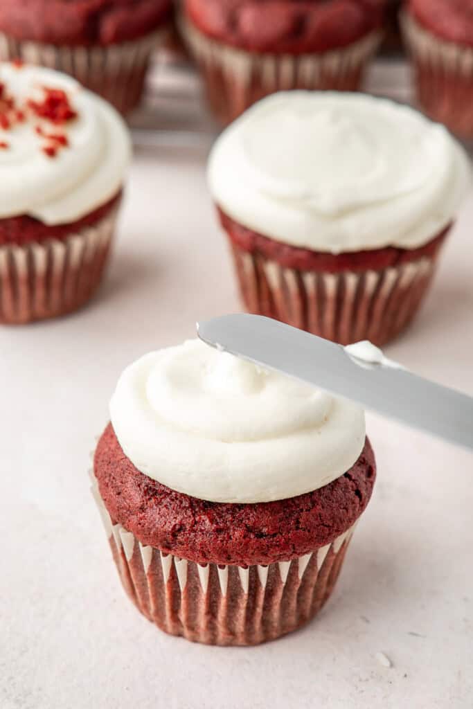 Frosting the red velvet cupcakes.