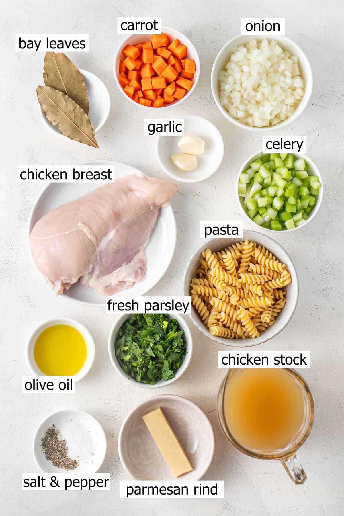 All ingredients needed to make pressure cooker chicken noodle soup laid out in bowls.
