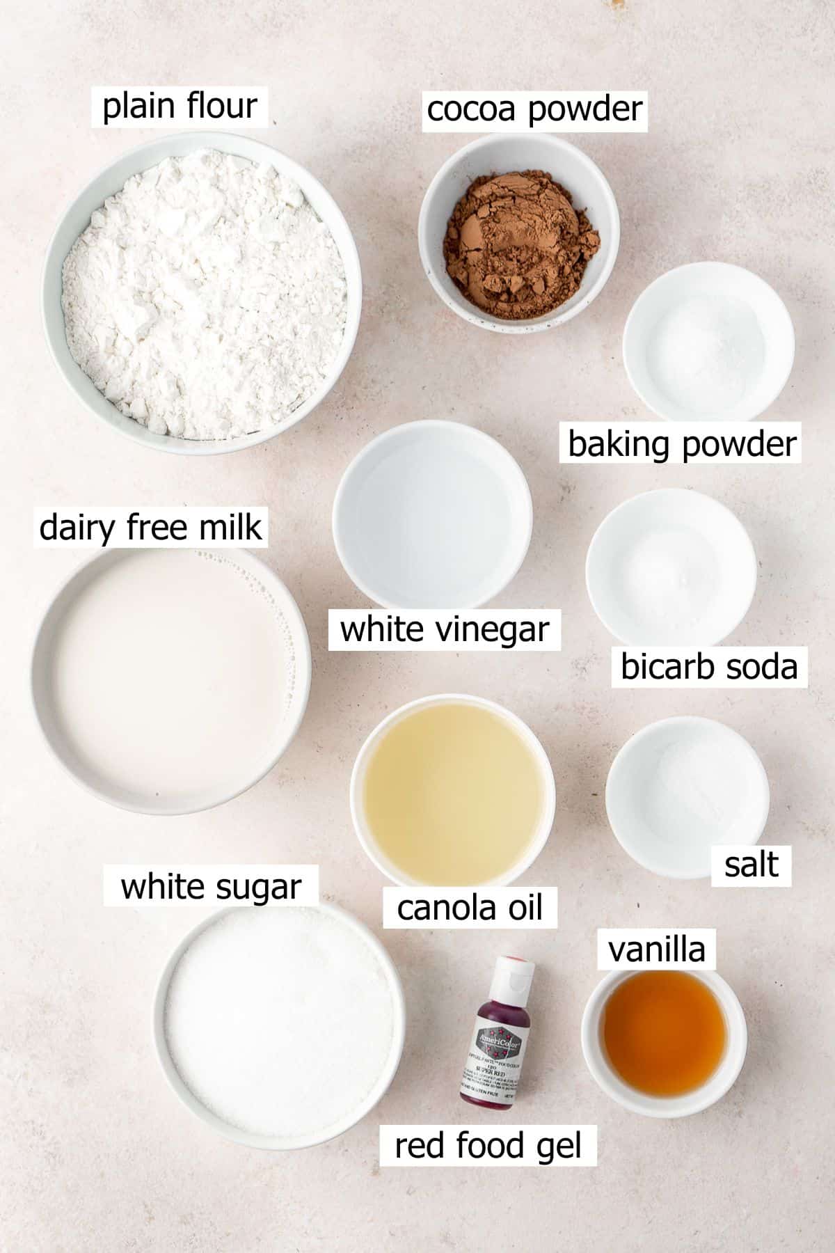 All ingredients needed to make red velvet cupcakes laid out in small bowls.