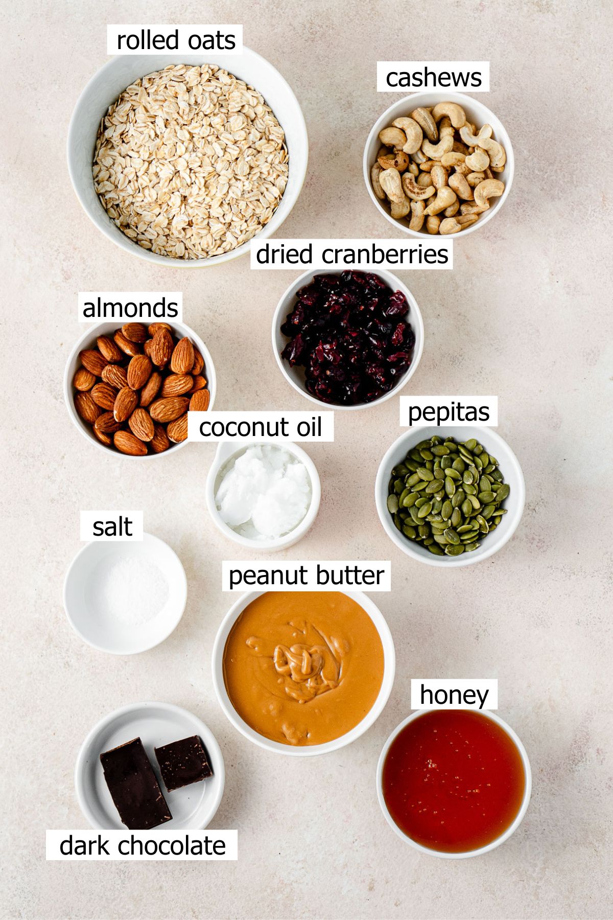 All ingredients needed to make peanut butter muesli bars laid out in small owls.