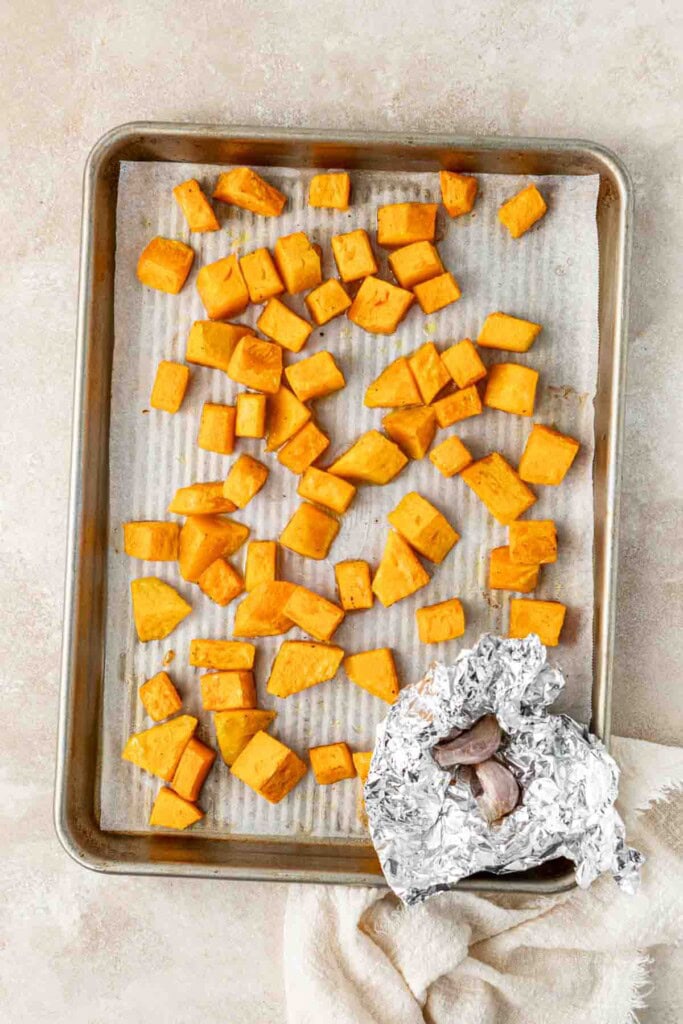 Roasted pumpkin and garlic on a baking tray.