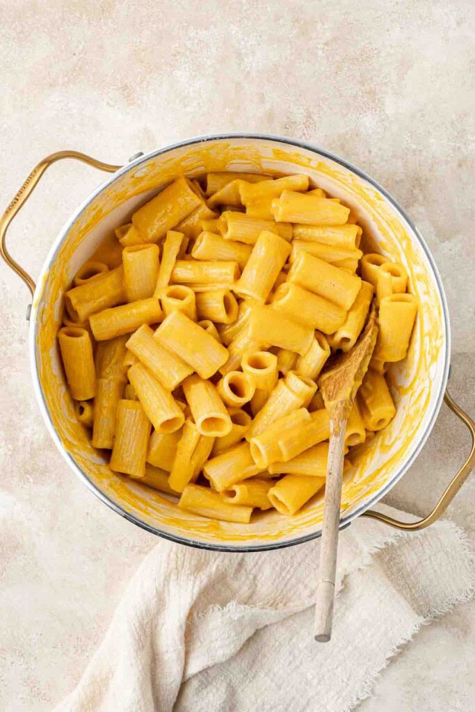 Creamy pumpkin sauce mixed through pasta in a pot.