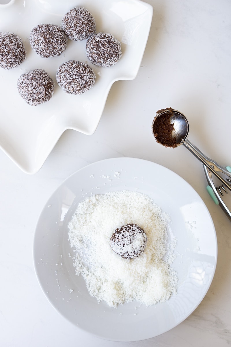 Making rum balls by rolling them in desiccated coconut