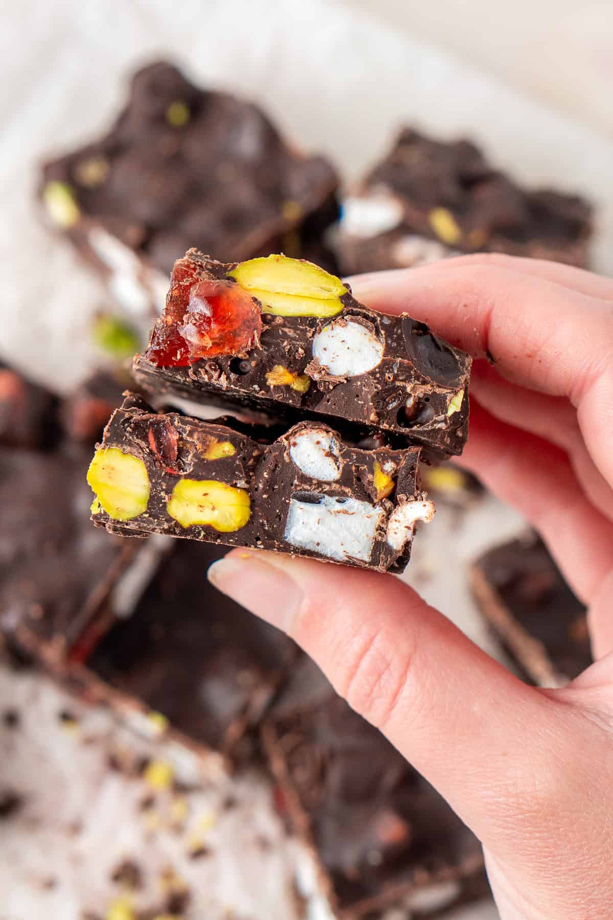 A hand holding two pieces of rocky road showing the add ins. 