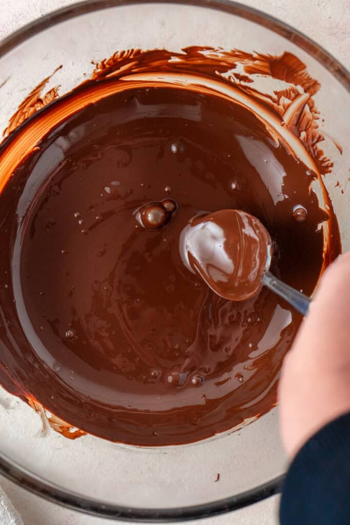 The melted dark chocolate in a mixing bowl with a spoon.