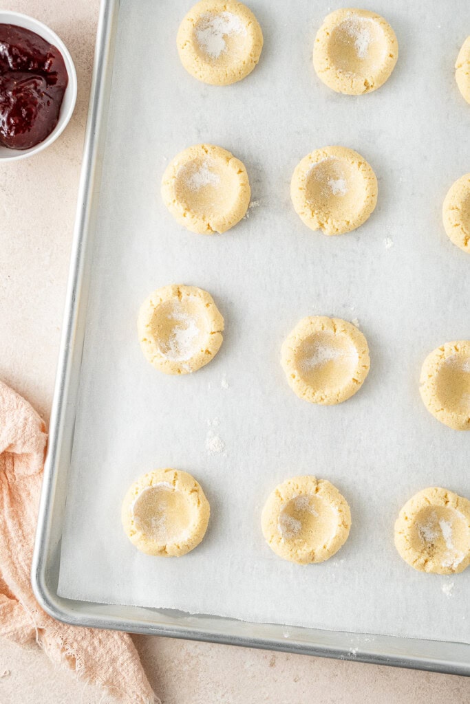 The rolled out cookies on a baking tray with indents.