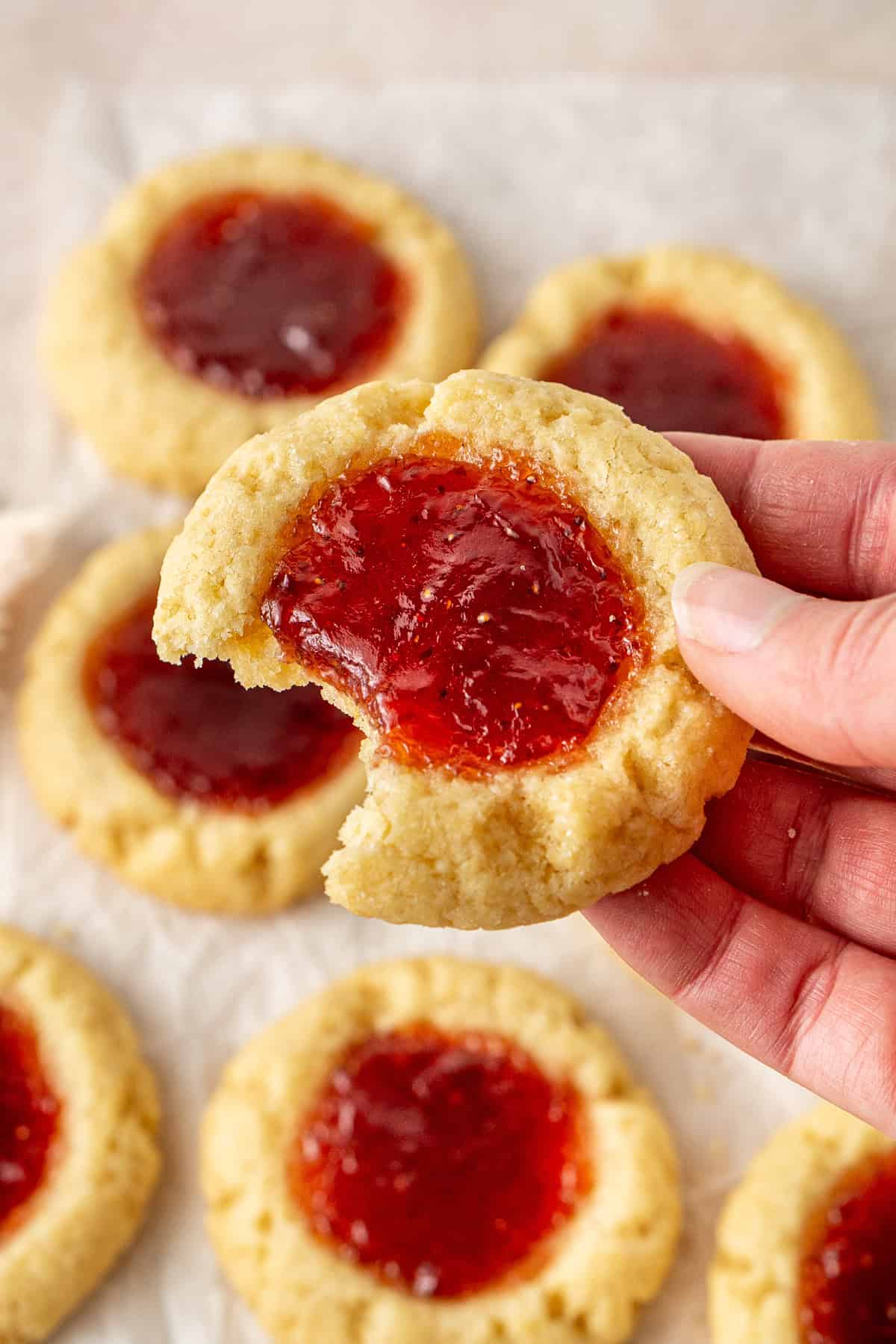 A hand holding a jam drop with a bite taken.