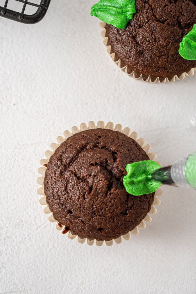 Piping the leaf design on the cupcake.