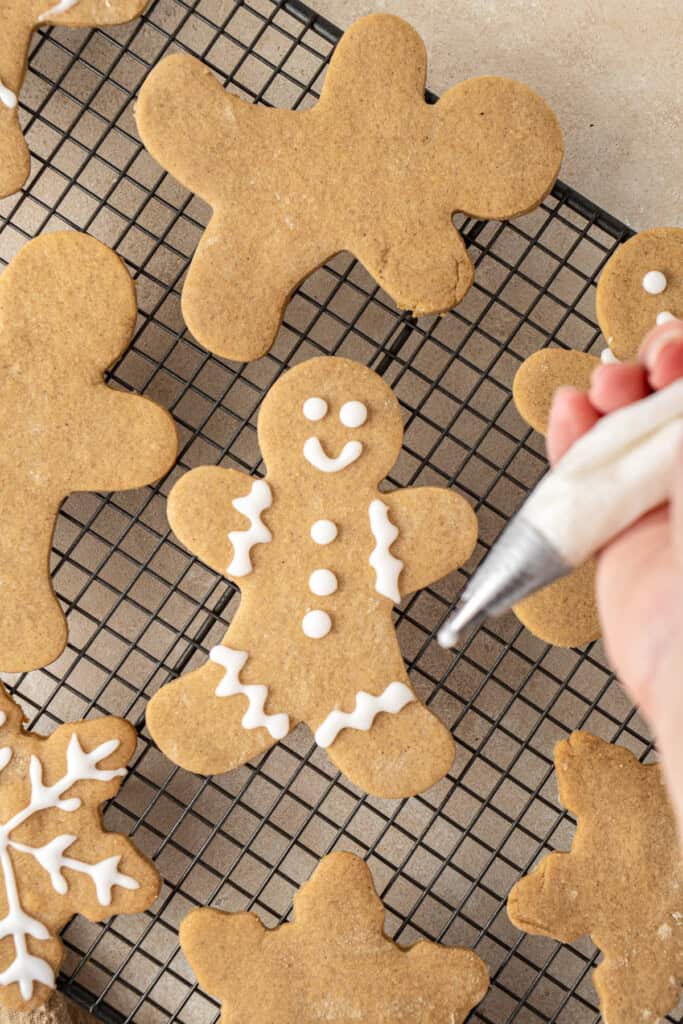 Decorating the dairy free gingerbread men with white icing.