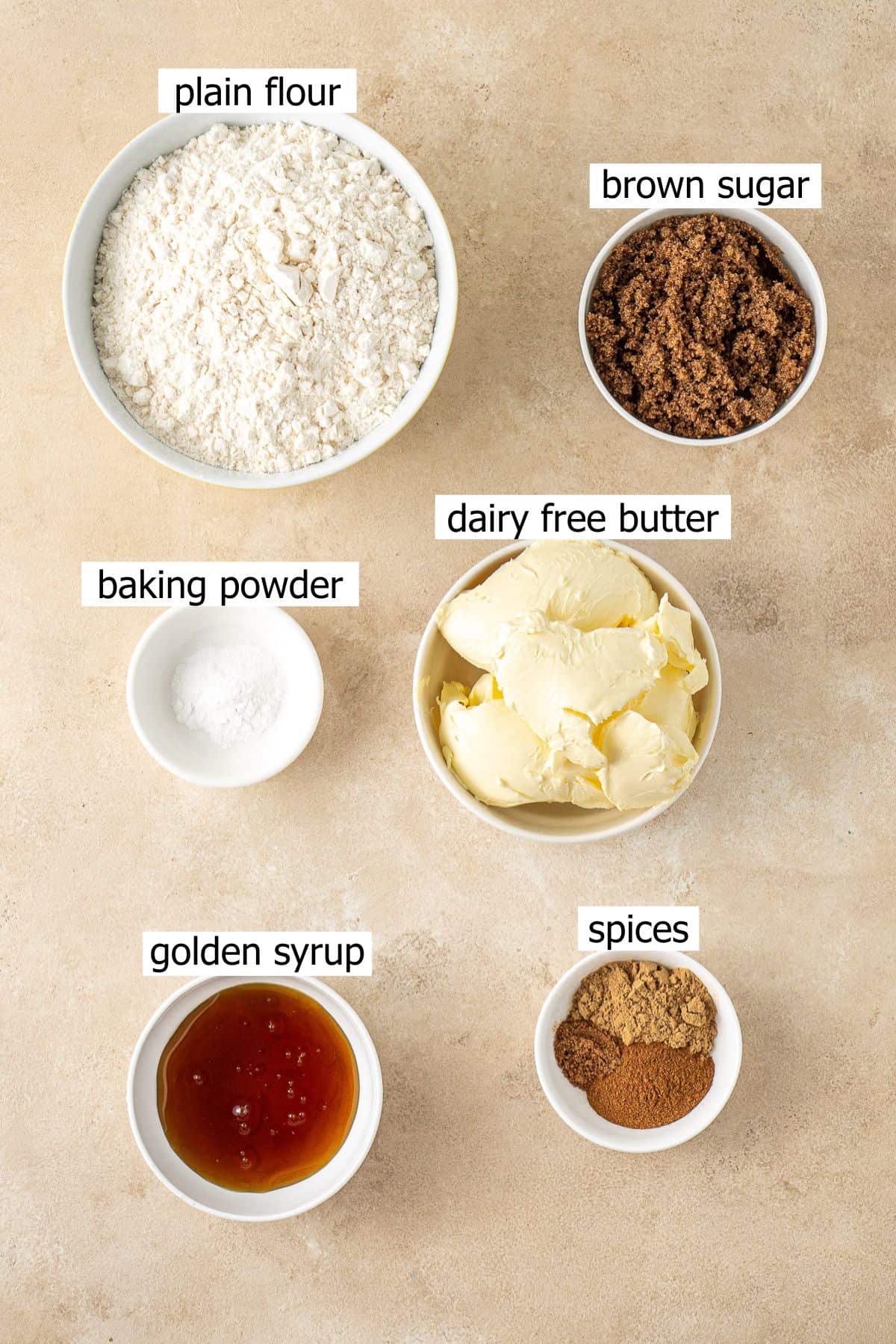 All ingredients needed to make vegan gingerbread men laid out in small bowls.