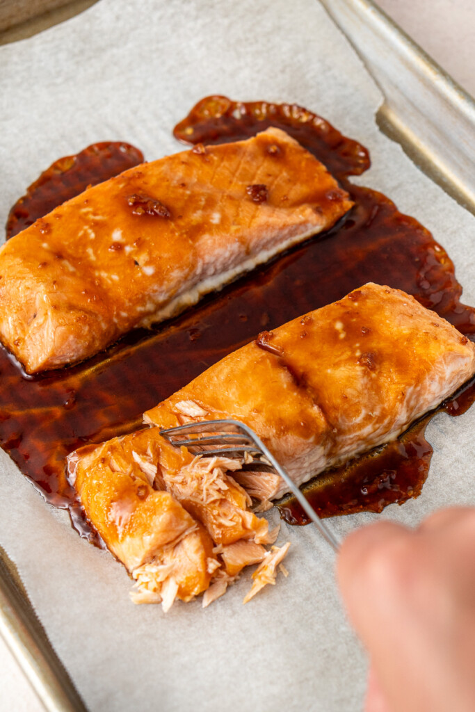 Flaking the cooked salmon using a fork.