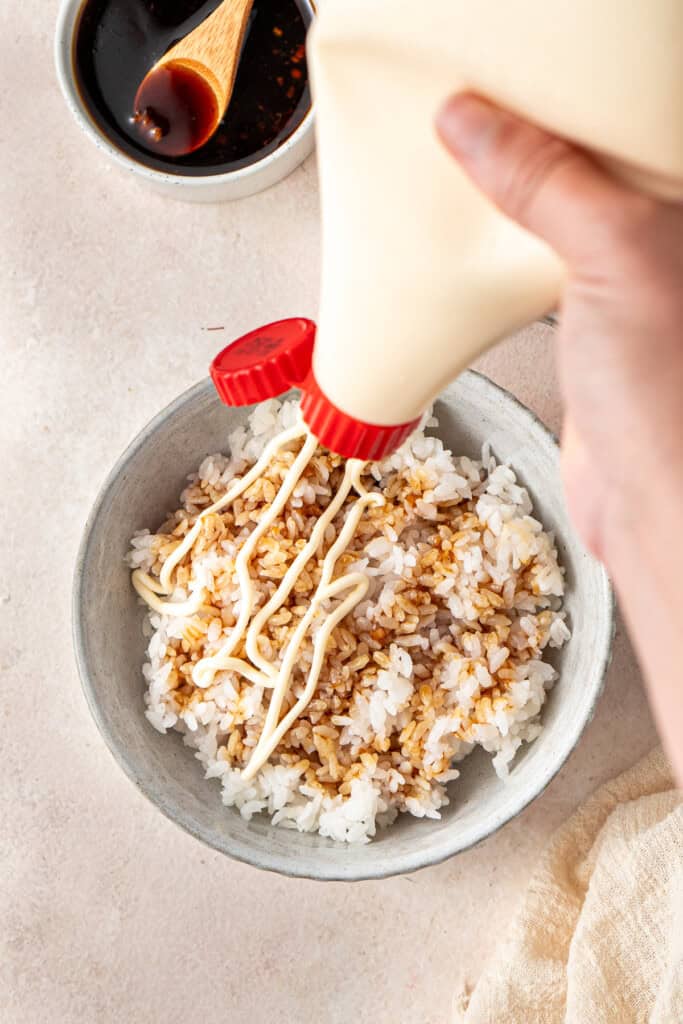 Adding some kewpie mayo to the rice bowl.